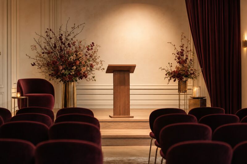 An elegant, intimate stage with a wooden lectern and warm lighting, set for a speaking event.